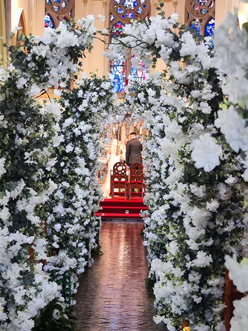 Enchanted white blossom arches lining a church aisle