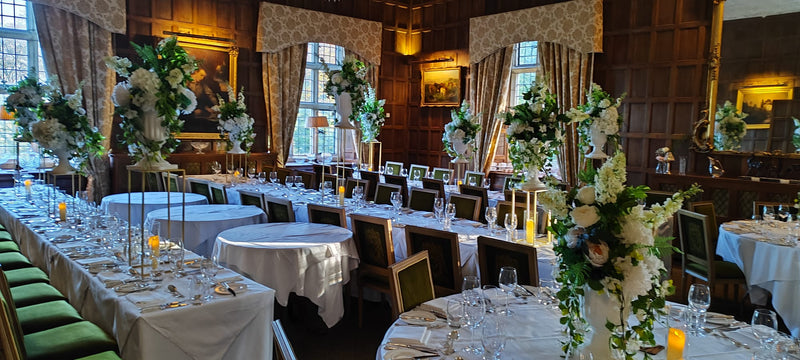 Wedding reception tables styled with tall white flowers and greenery