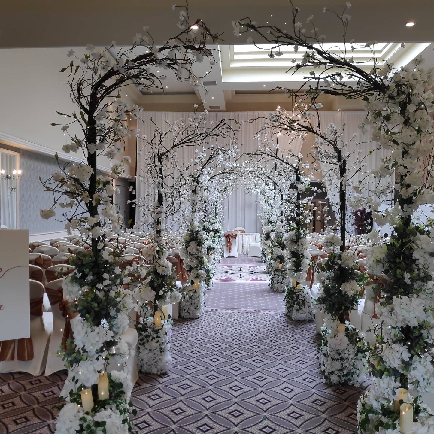 "Enchanted Wedding Ceremony Package set up for an indoor civil ceremony with five glowing arches and aisle décor."