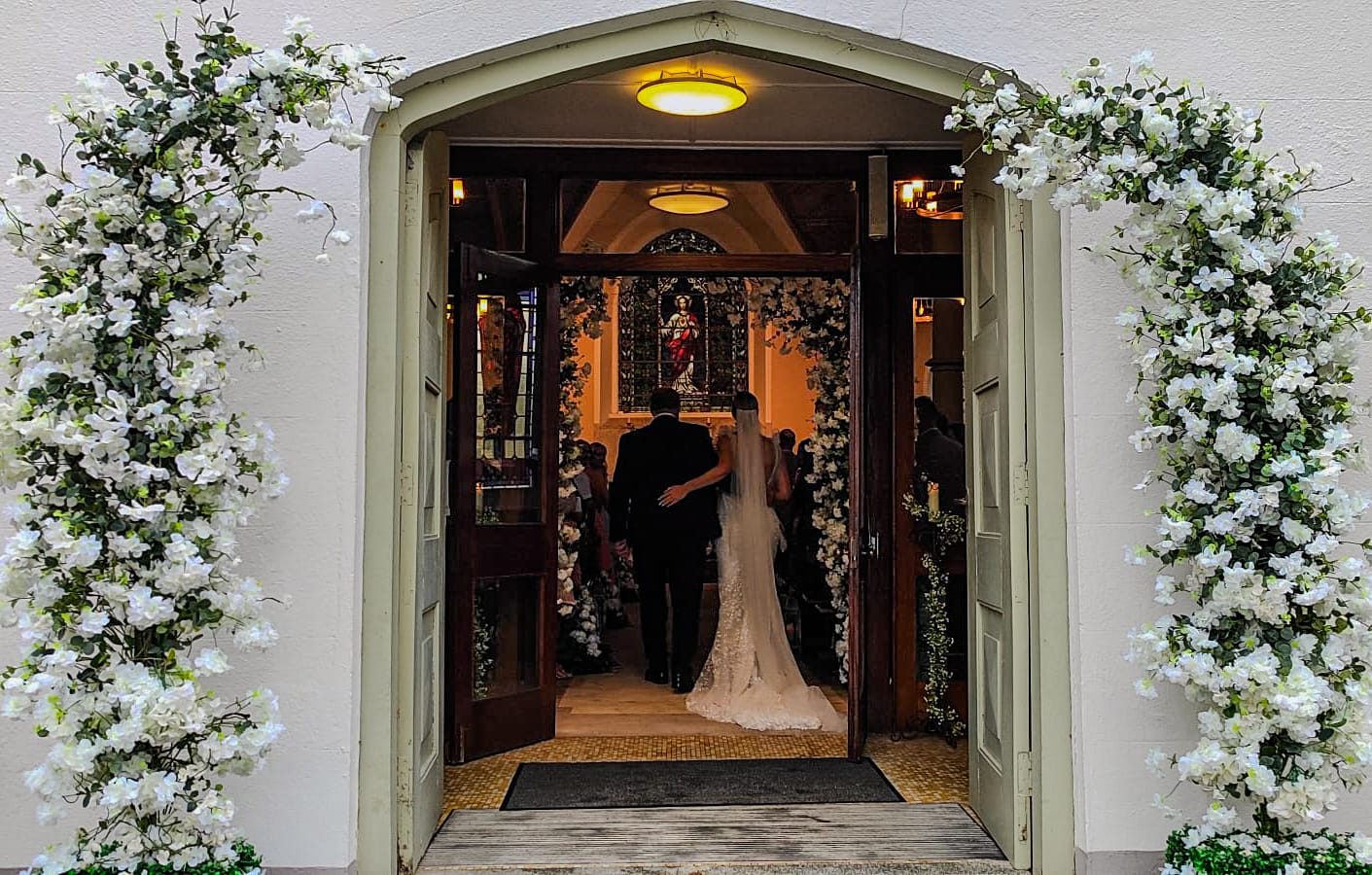 Meadow wedding ceremony package with white floral arches, aisle flowers and lanterns