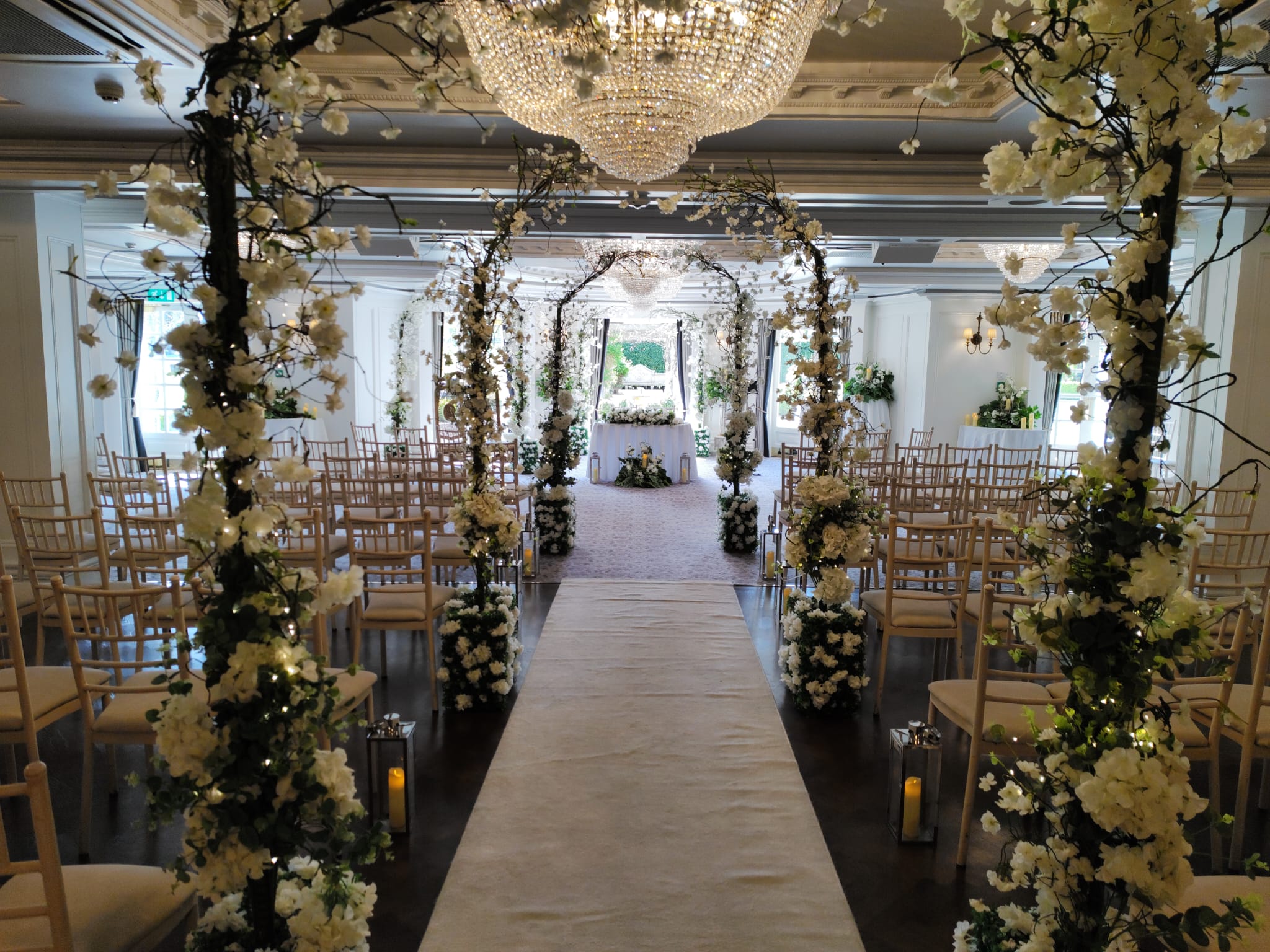 Bride and groom walking down an aisle framed by Enchanted wedding blossom tree arches