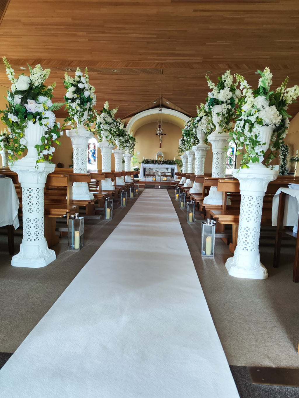 Leoni wedding package church aisle with tall white pedestal florals and lanterns