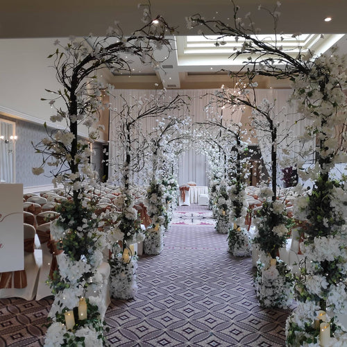Enchanted wedding ceremony aisle with glowing blossom arches and lanterns