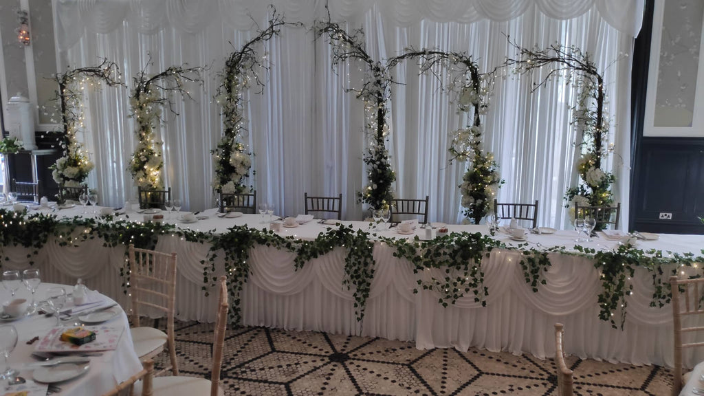 Full wedding reception decor with floral backdrop and styled guest tables