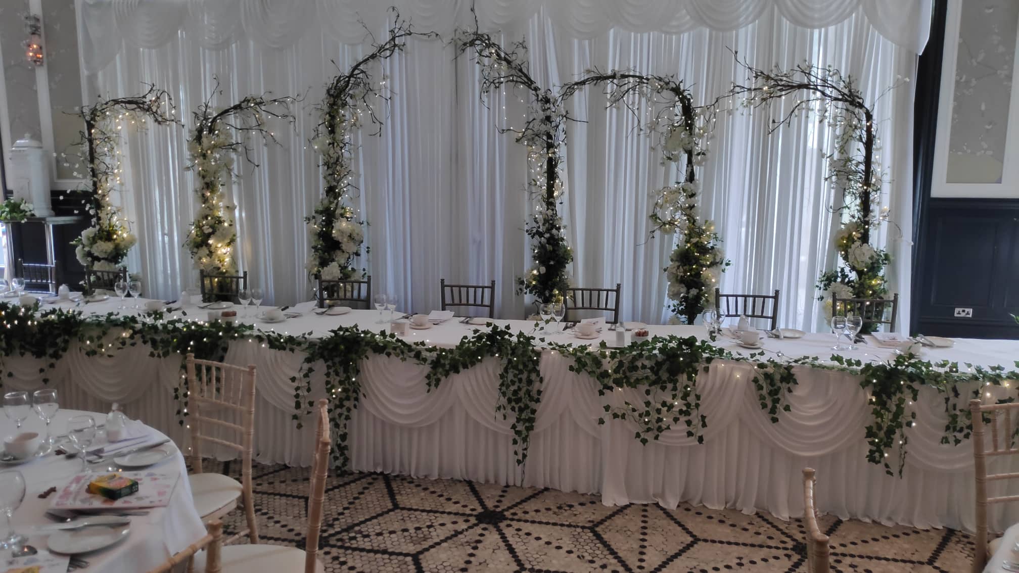 Full wedding reception decor with floral backdrop and styled guest tables