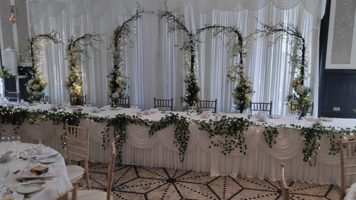 Full wedding reception decor with floral backdrop and styled guest tables