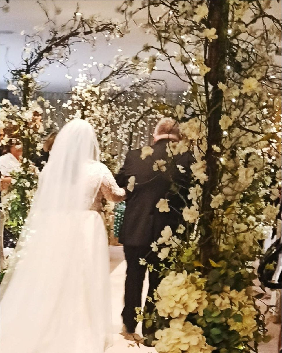 Bride and groom exchanging vows beneath blossom wedding decor