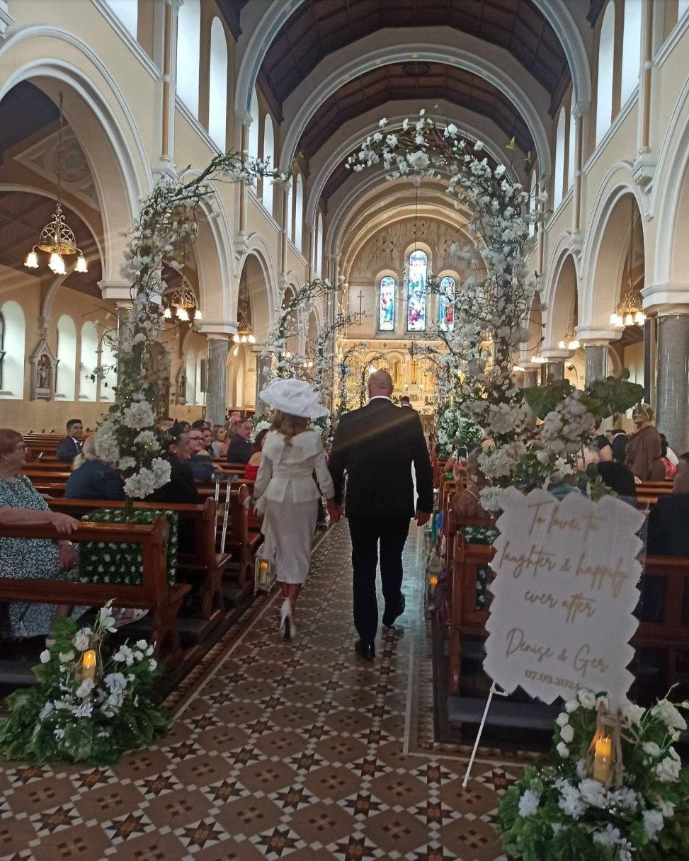 Bride and groom walking through a cathedral aisle surrounded by wedding guests