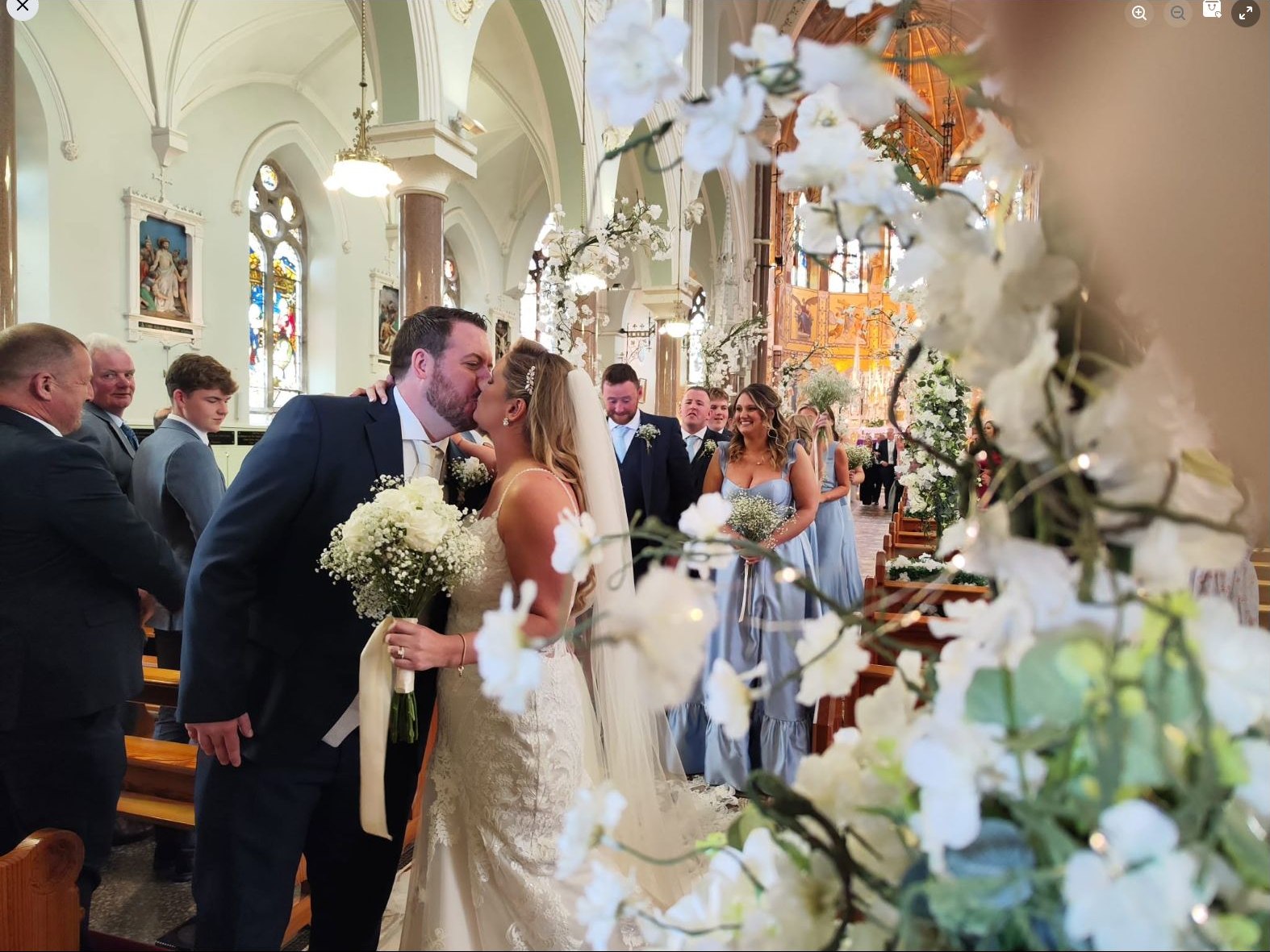 Bride and groom during their wedding ceremony with white blossom aisle flowers